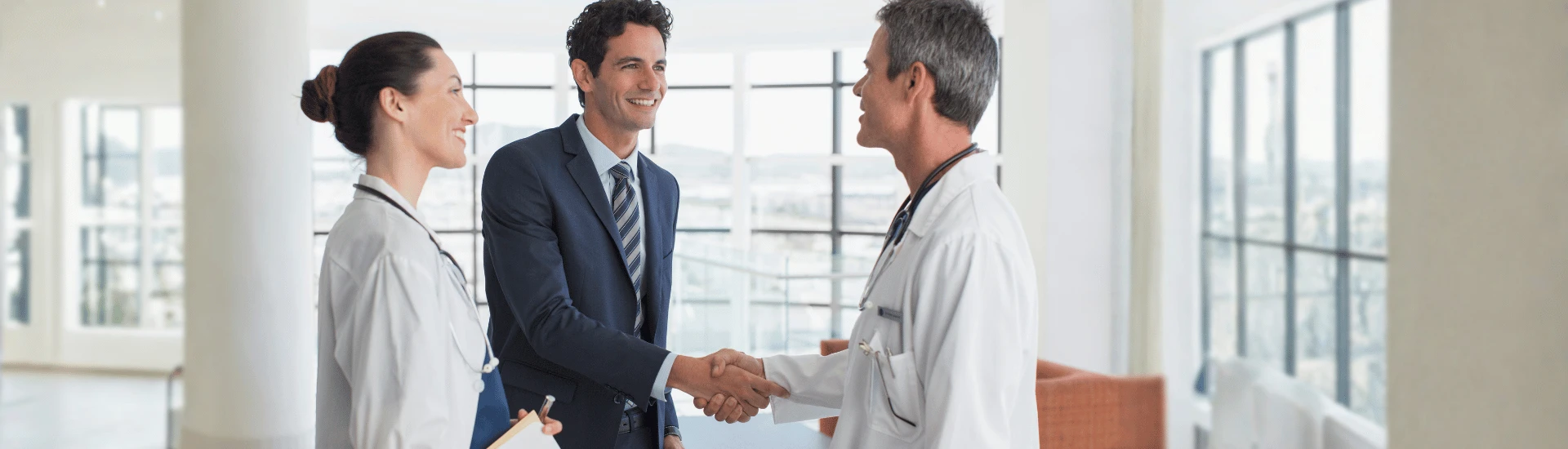 Executivo cumprimentando médicos. A Farmacoeconomia comprova o valor do seu produto.